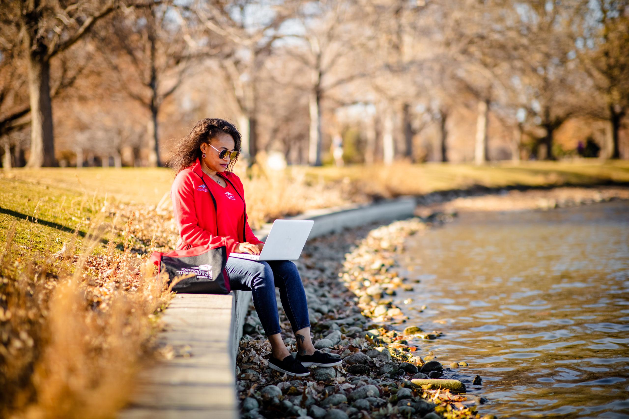 Karena Beckham in 密歇根州立大学丹佛 swag, working on a laptop in City Park.